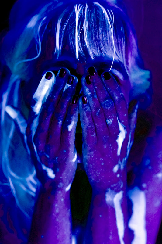 Woman covered in glowing paint under blacklight