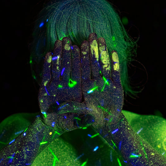 A person with hands covered in glowing green and blue fluorescent paint